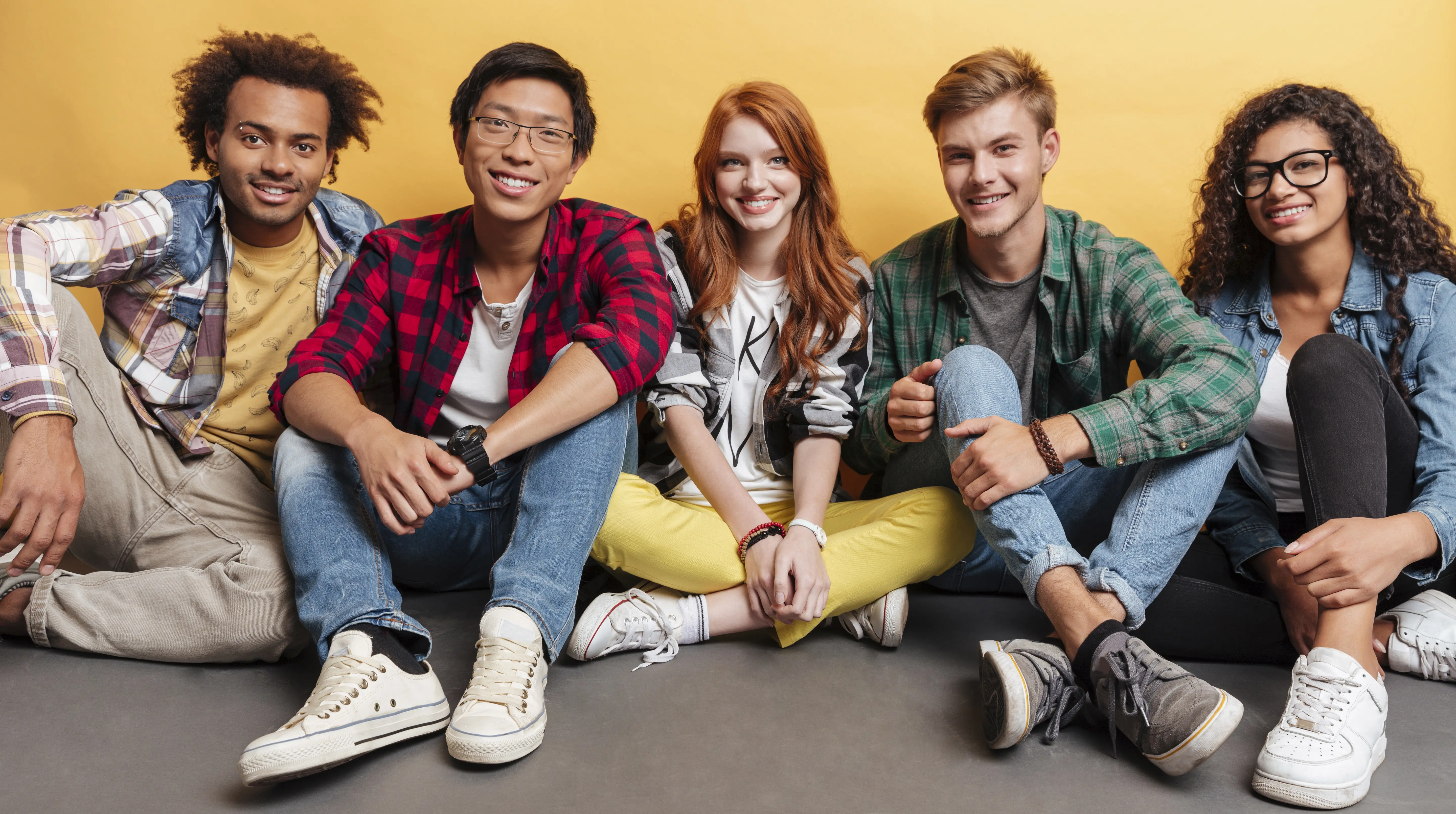 Multiethnic group of smiling friends sitting on the floor together