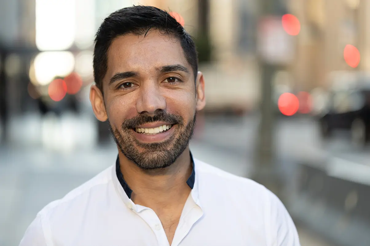 Young Latino Hispanic man in city smile happy face