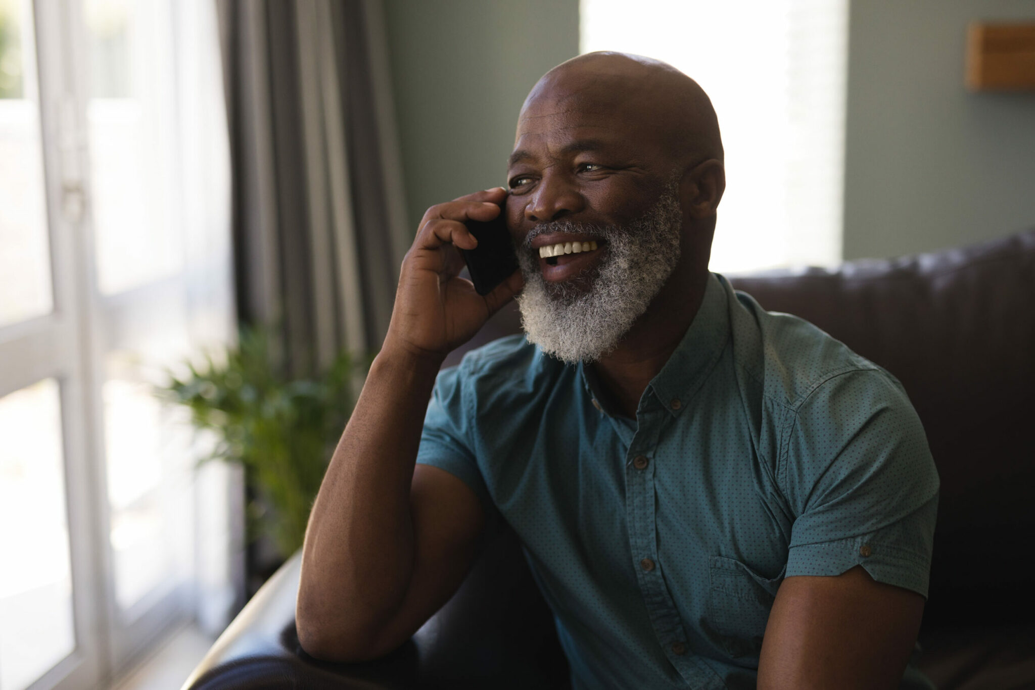 Older Afro-american man on cell phone talking and laughing.