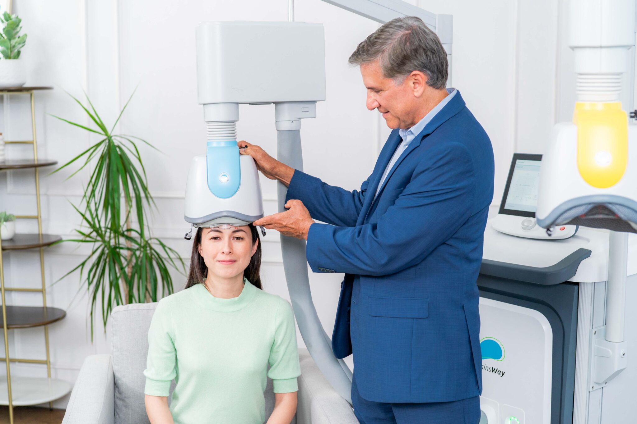 A doctor helps fit a TMS helmet on top of a patient's head